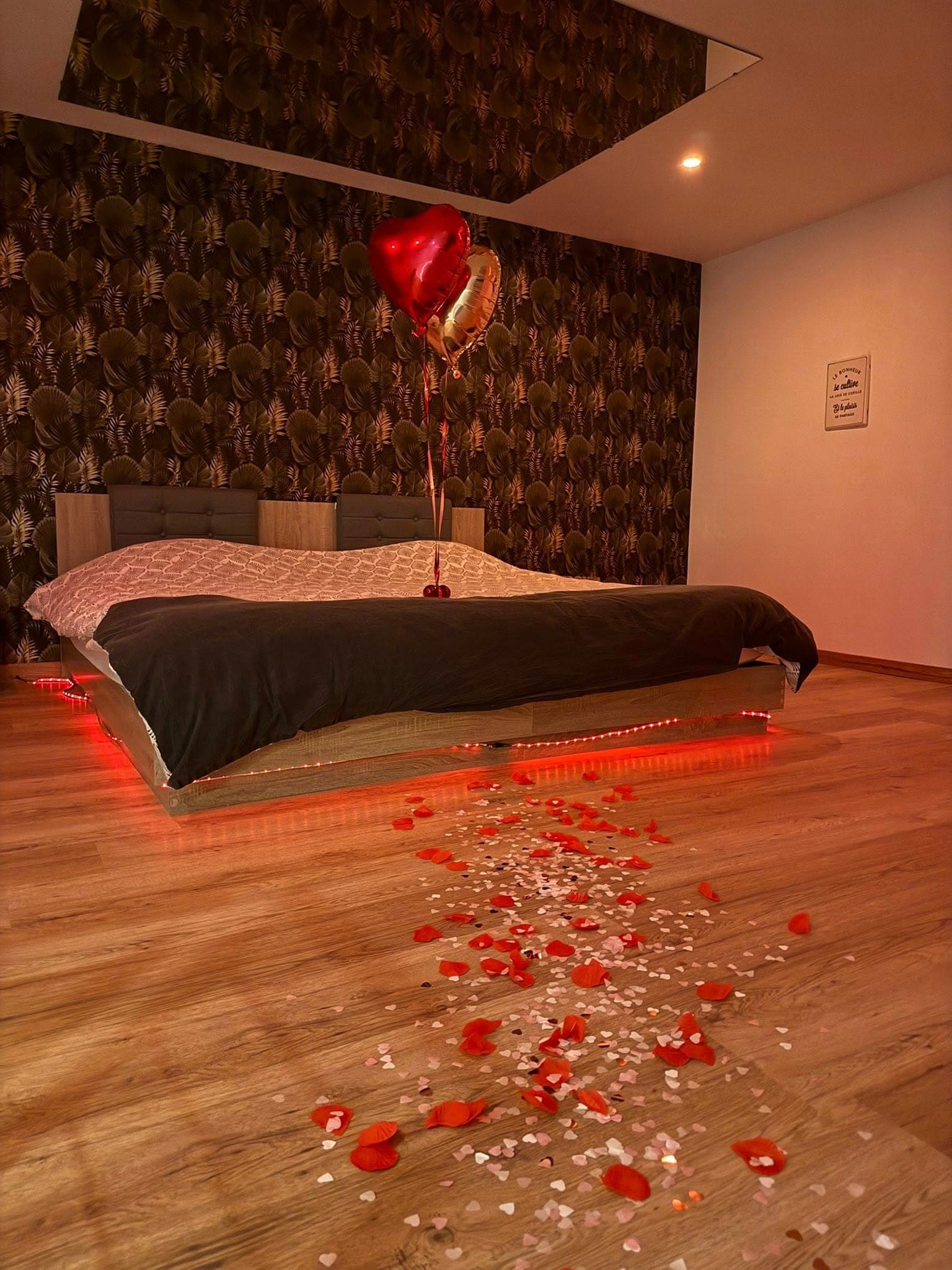 Chambre romantique avec lit flottant LED, ballons cœur et pétales de rose